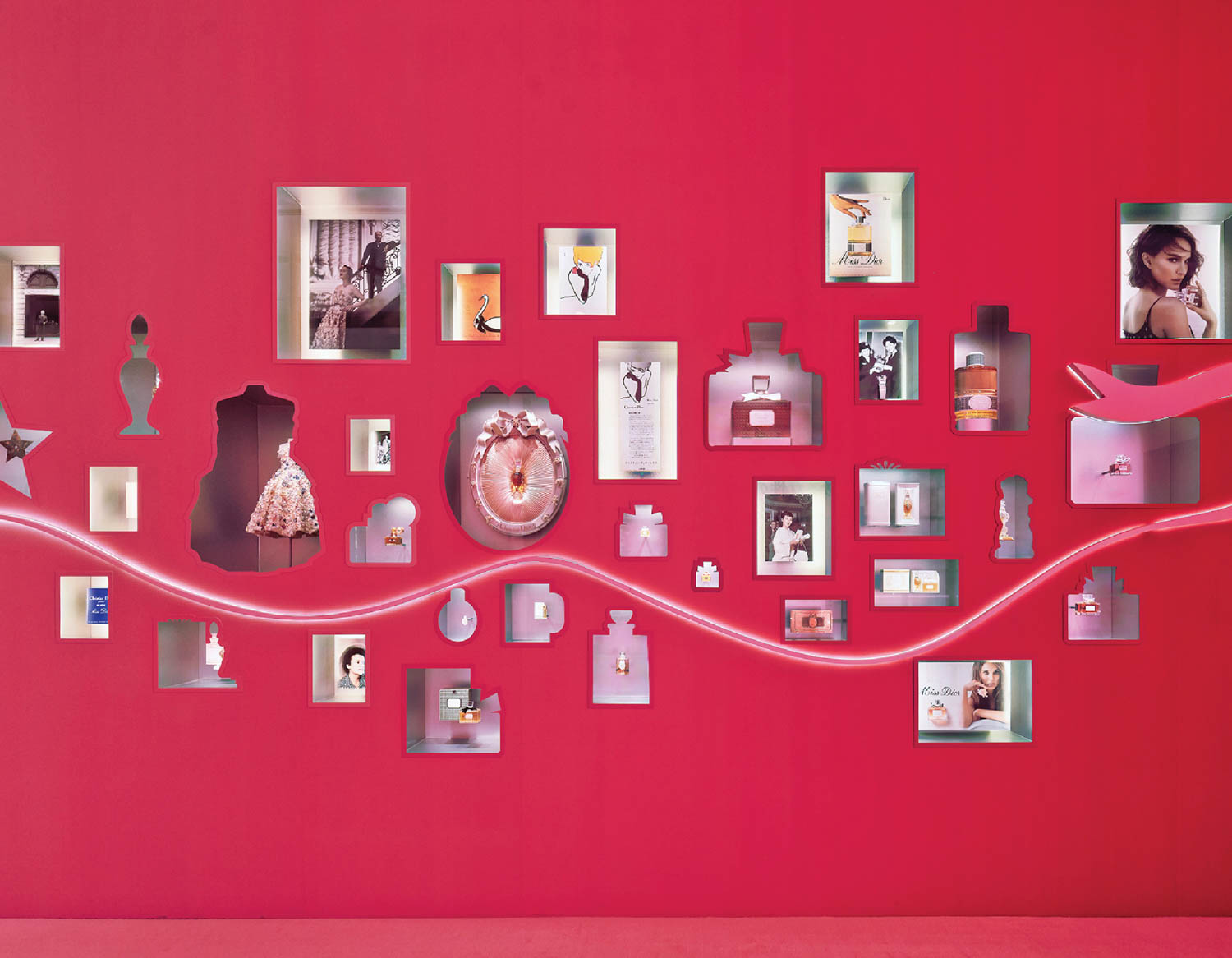 cut outs of miss dior perfume bottles on a red wall