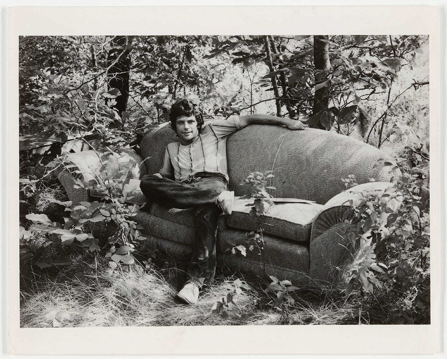 A man sitting on a couch in the woods