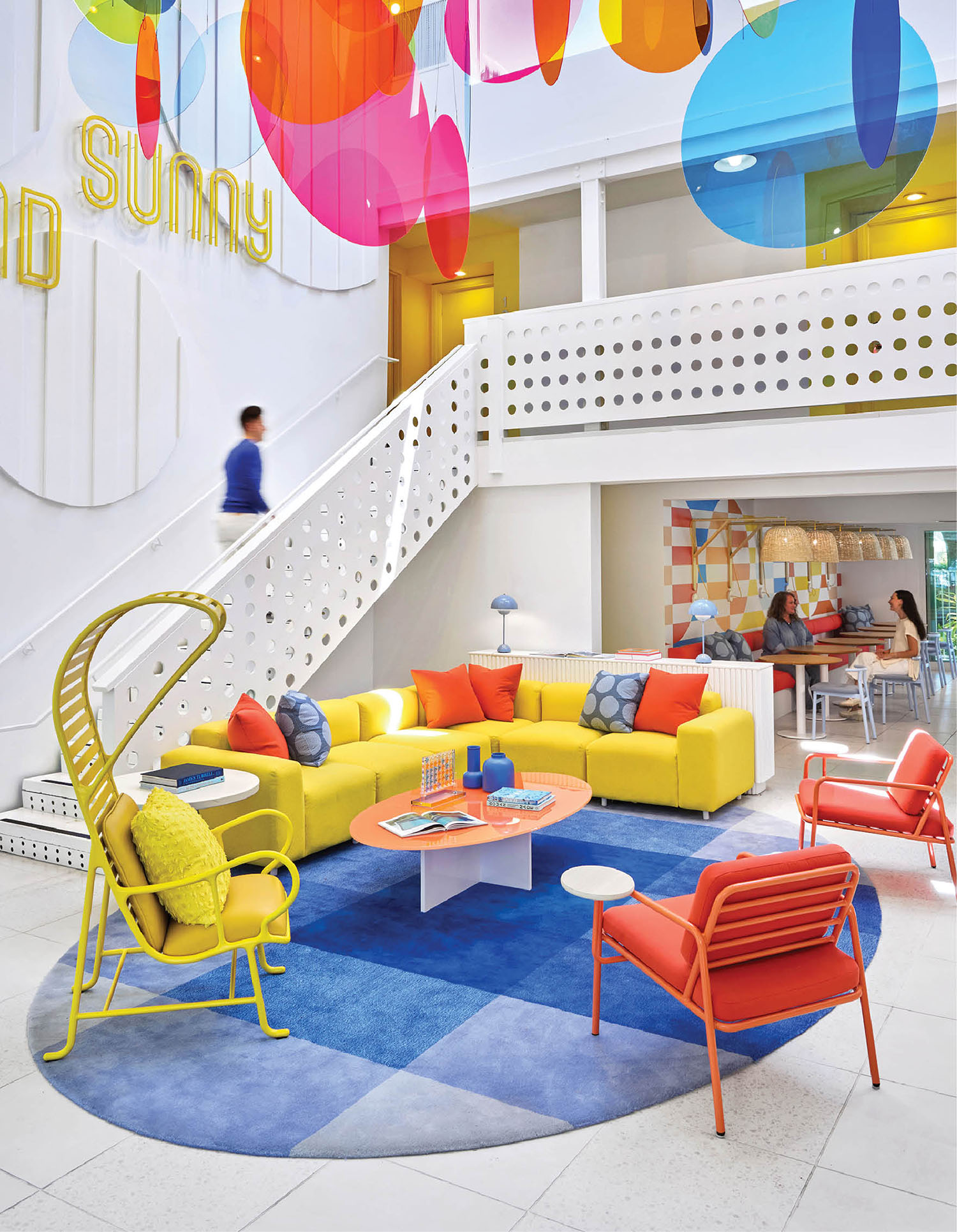 A colorful living room with a staircase and a colorful couch