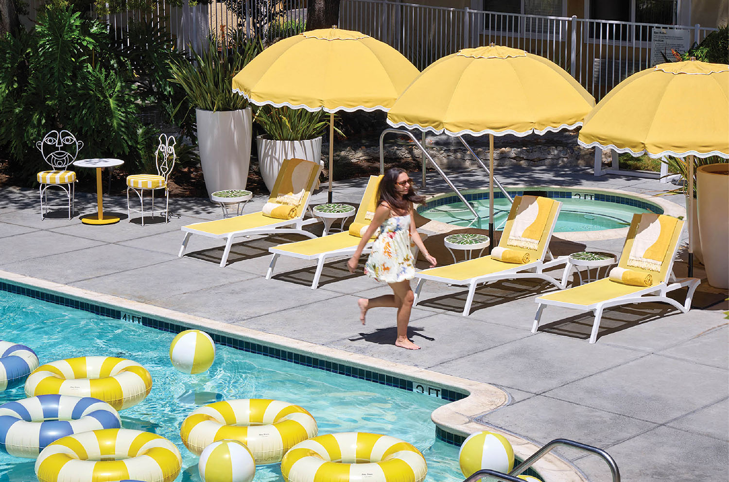 A woman sitting in a pool with yellow and blue beach chairs