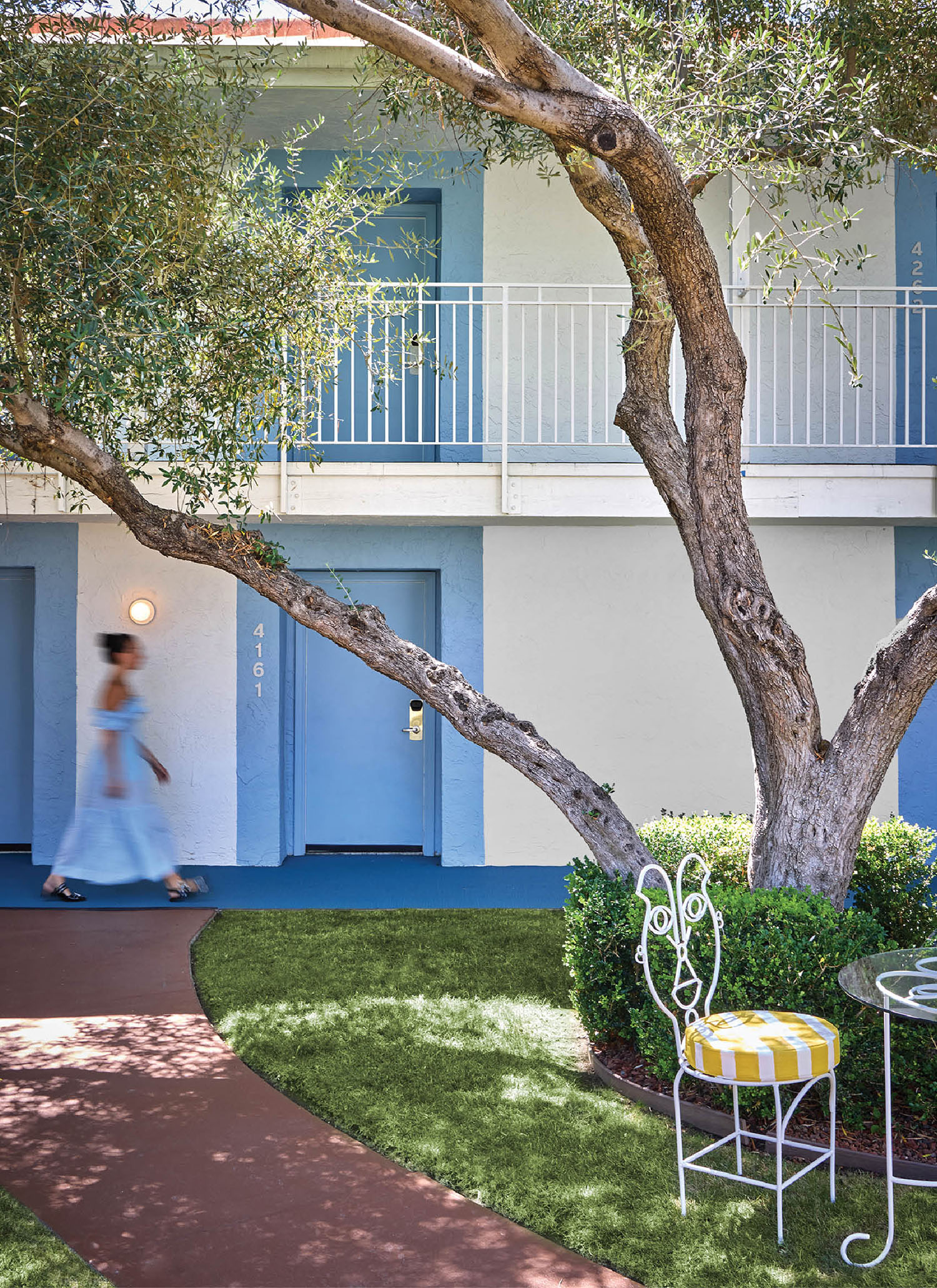 A woman walking past a tree in a courtyard