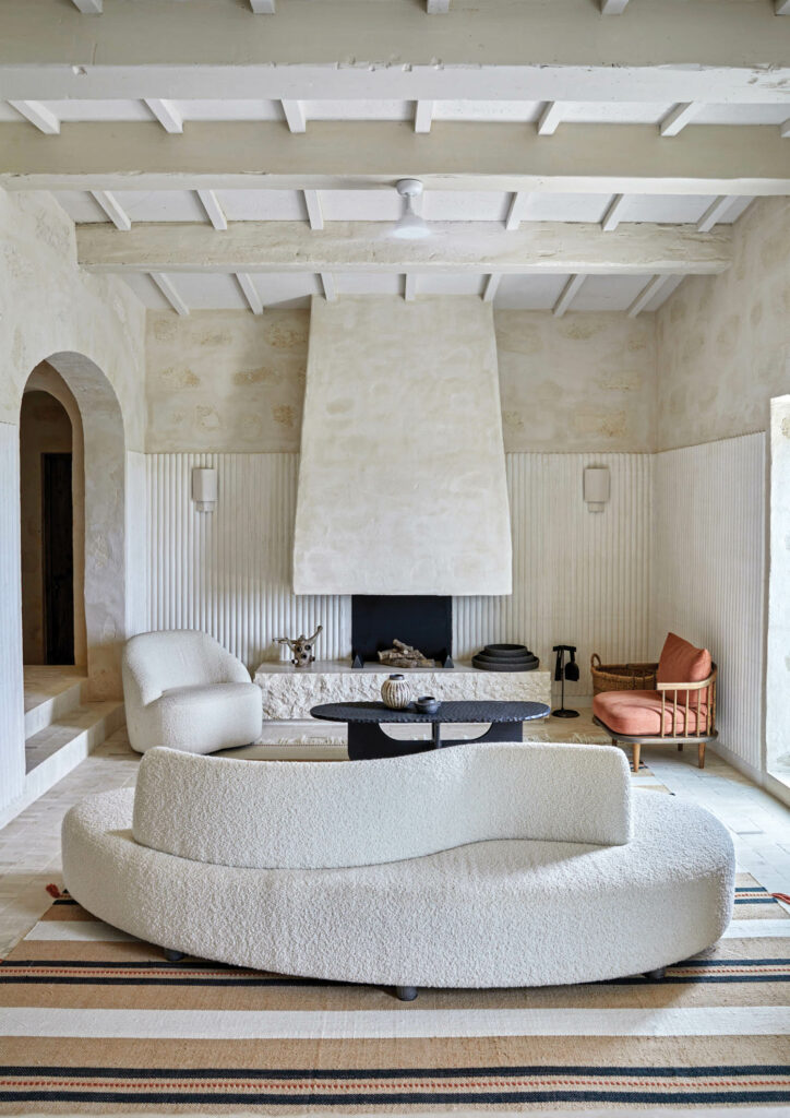 a curvy cream sofa wraps around the fireplace