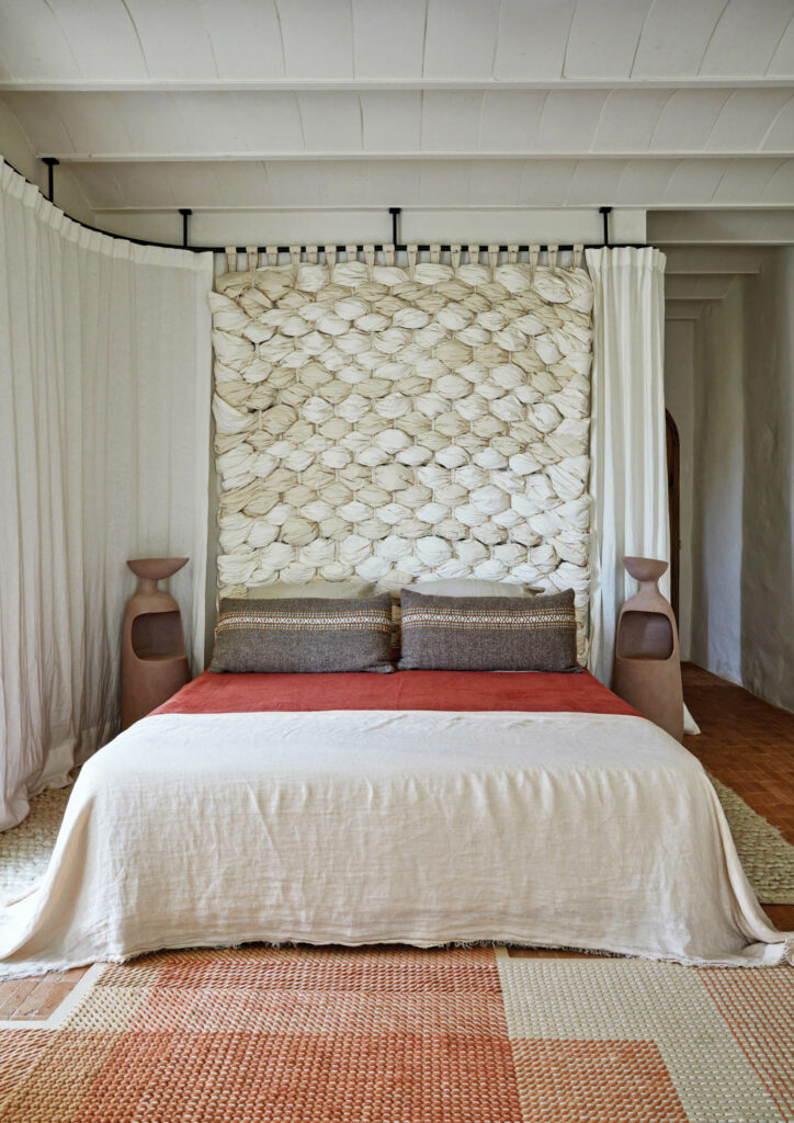 a bed with custom pedestals and a wood headboard wrapped in cotton