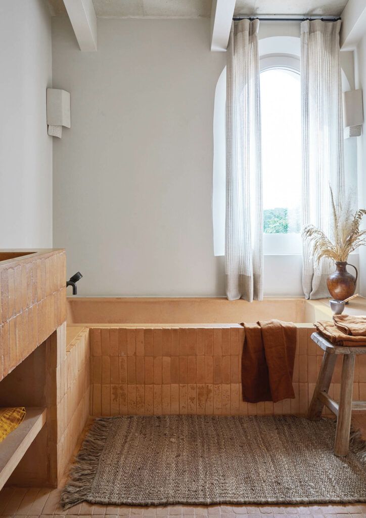 Tub and sink in terra-cotta tile in a guest bathroom.