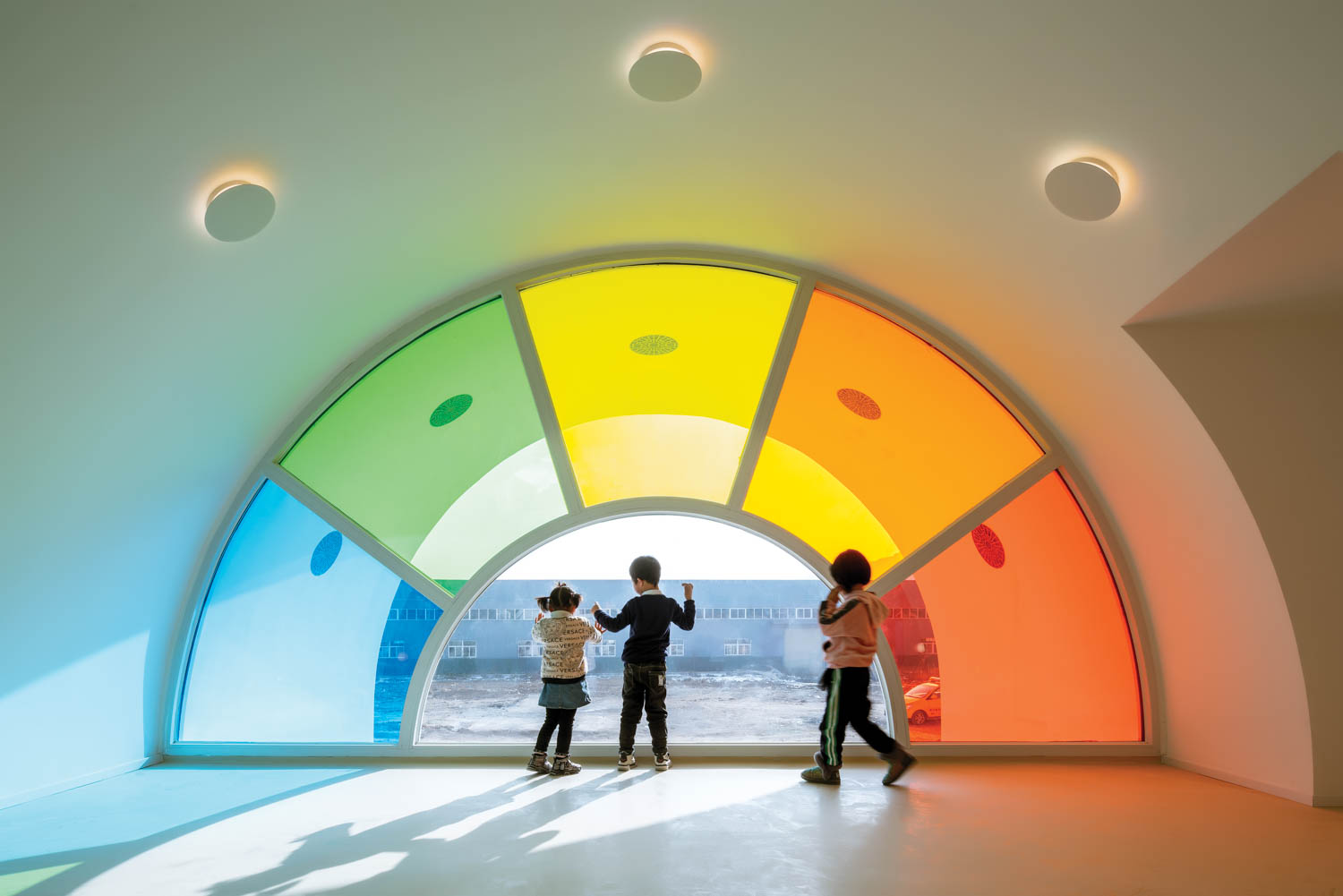 three children play near a window framed by a rainbow