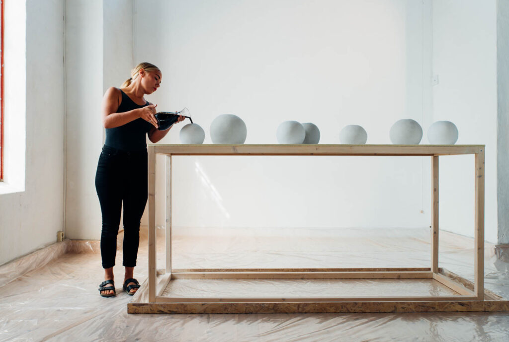 a woman leaning on a table with white ceramic orbs