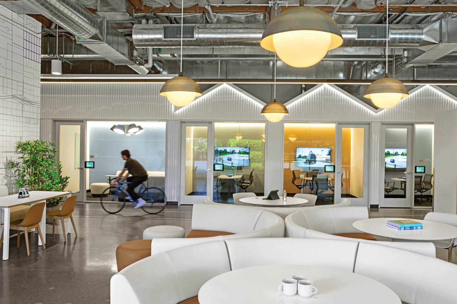 a man bikes through a tech office with white curved couches