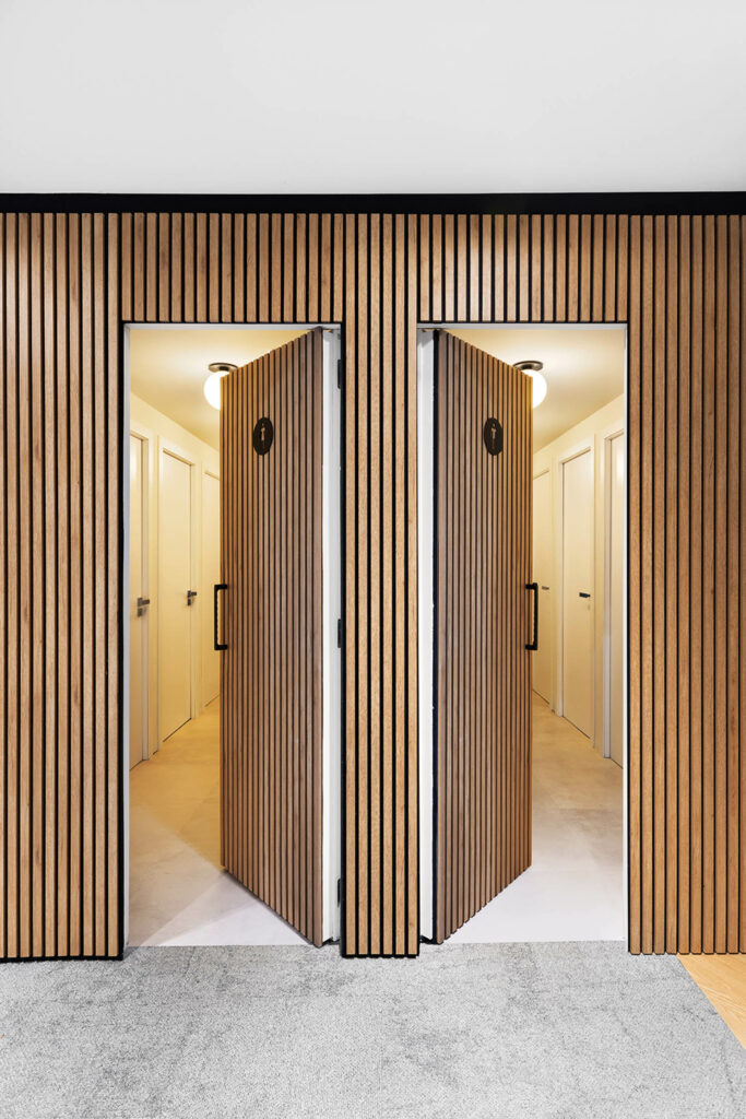 slated wood walls with two open doors to the restrooms