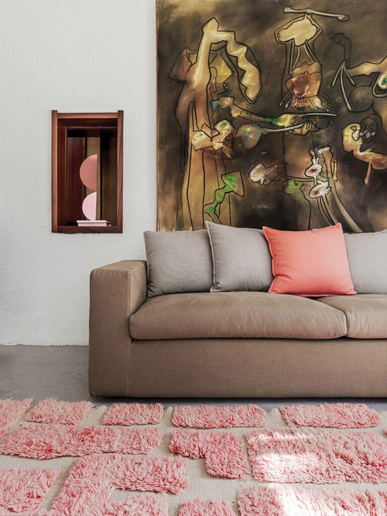 a tope couch with a peach accent pillow and artwork above