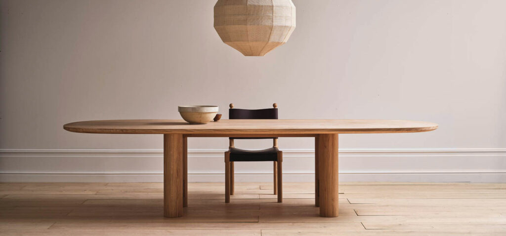 a minimalist wood table with black leather chair and pendant light above