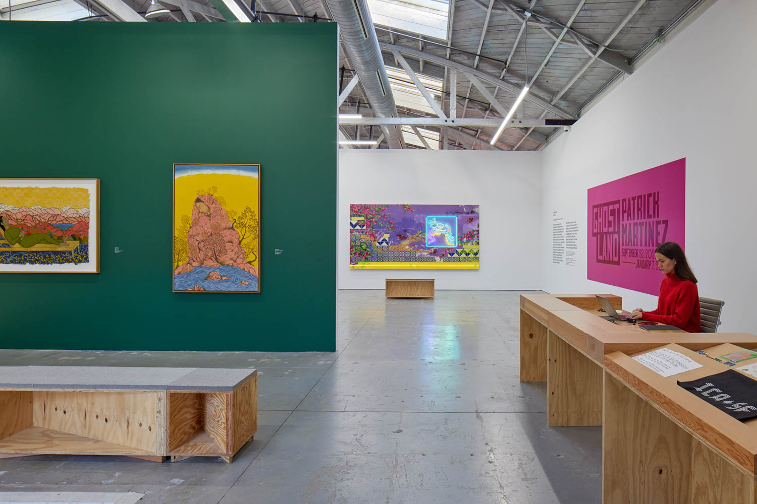 gallery space with dark green wall and lots of seating