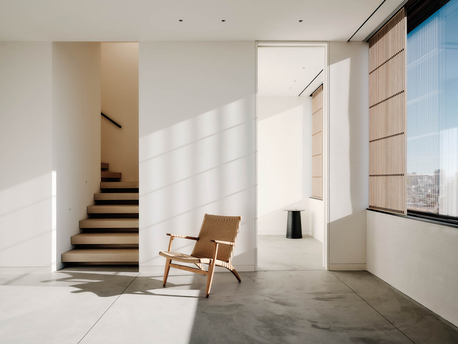 four-story stairwell with white walls, chair and shutters that bring in light