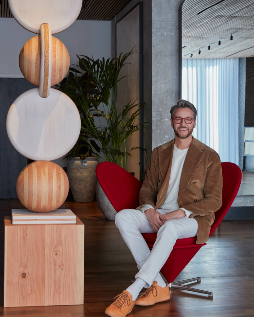 Jacu Strauss sitting next to a sculpture with stacked orbs