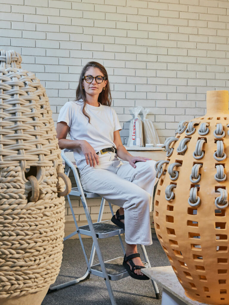 Xanthe Somers sitting with her ceramic work