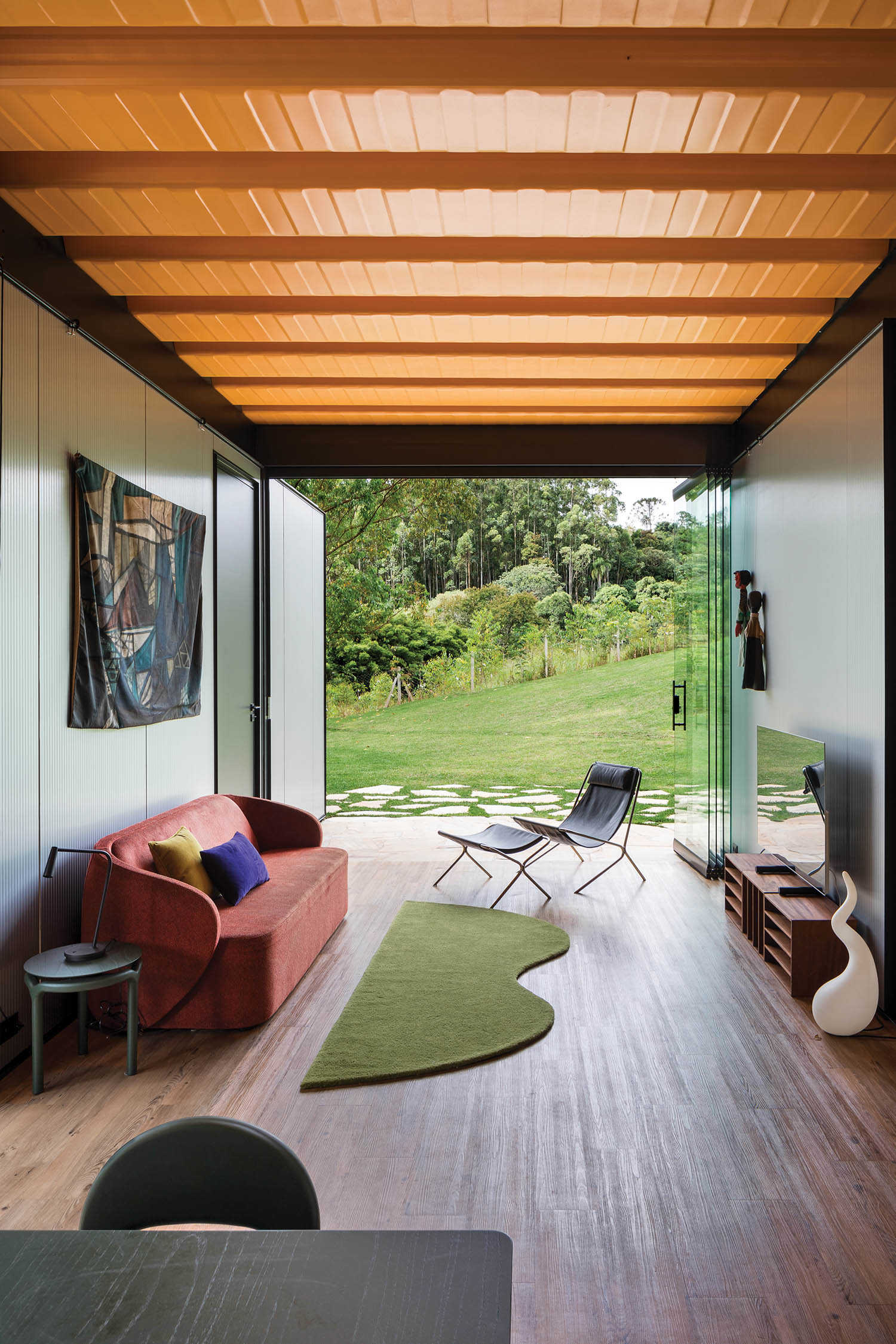 view of the living area with a funky red couch, green rug and view to the surroundings