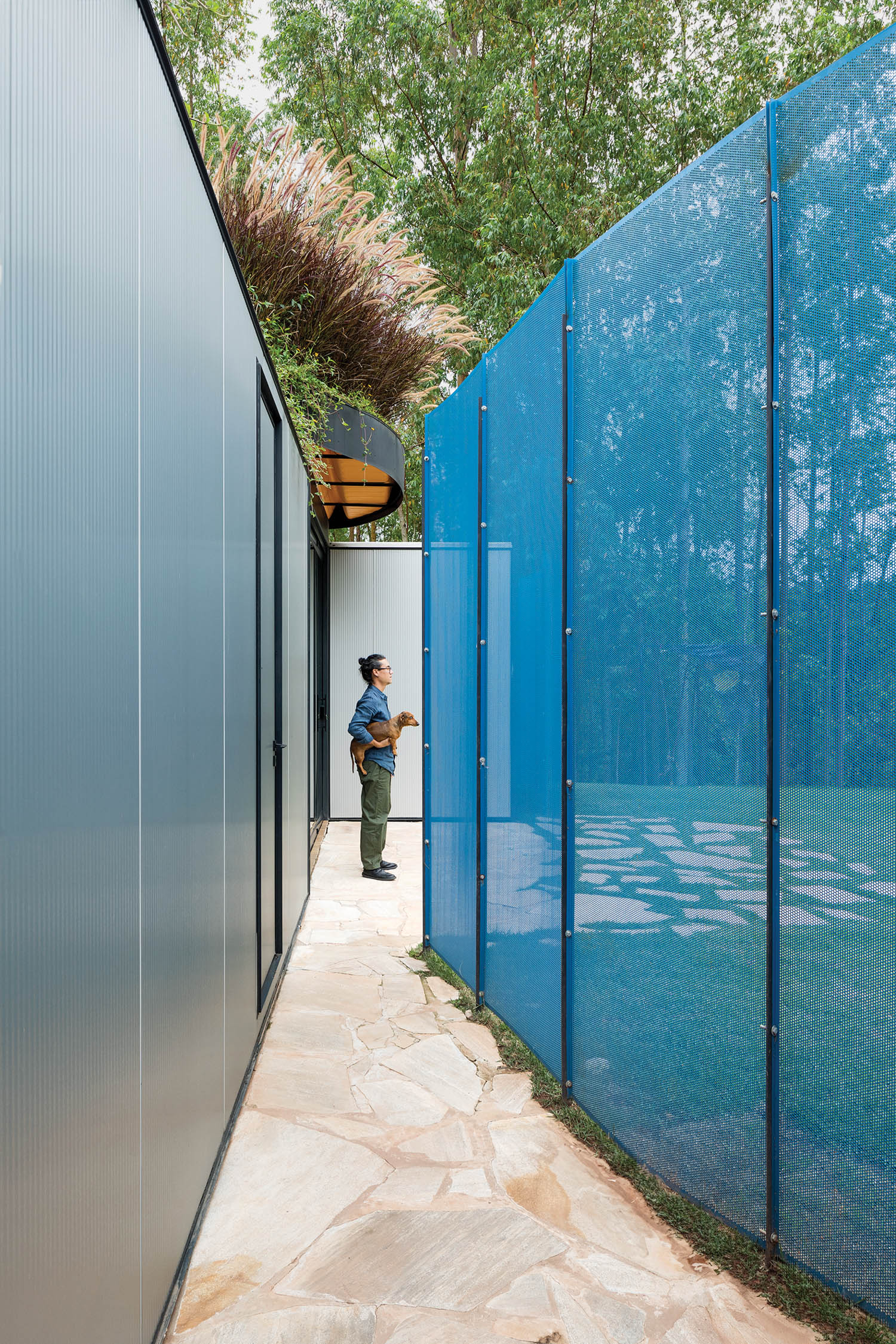 person standing in between a perforated-metal screen and the home's walls