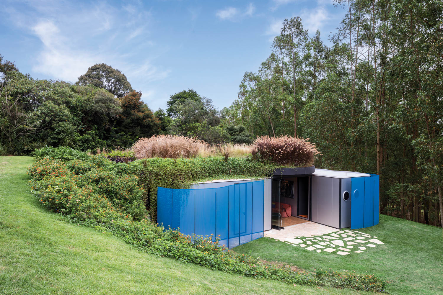 blue paneled building that is built into a grassy landscape