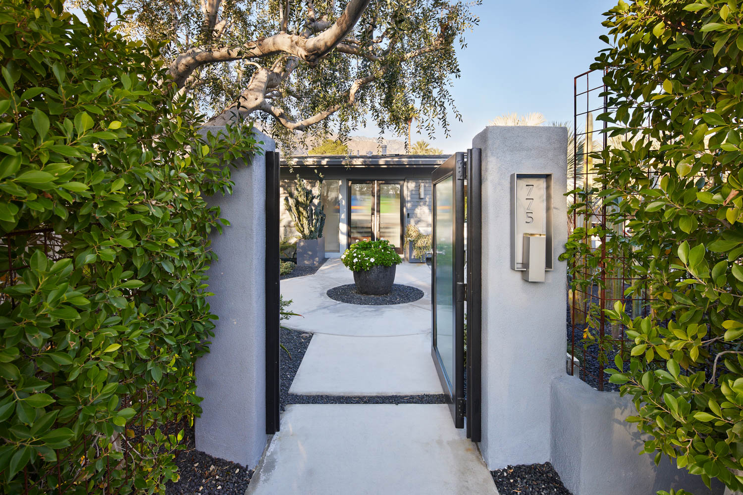 lush entryway with white pillars and gates