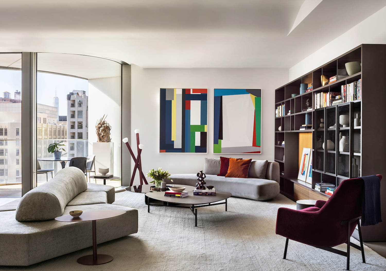 living area with multicolored artwork, dark bookcase and grey sofa