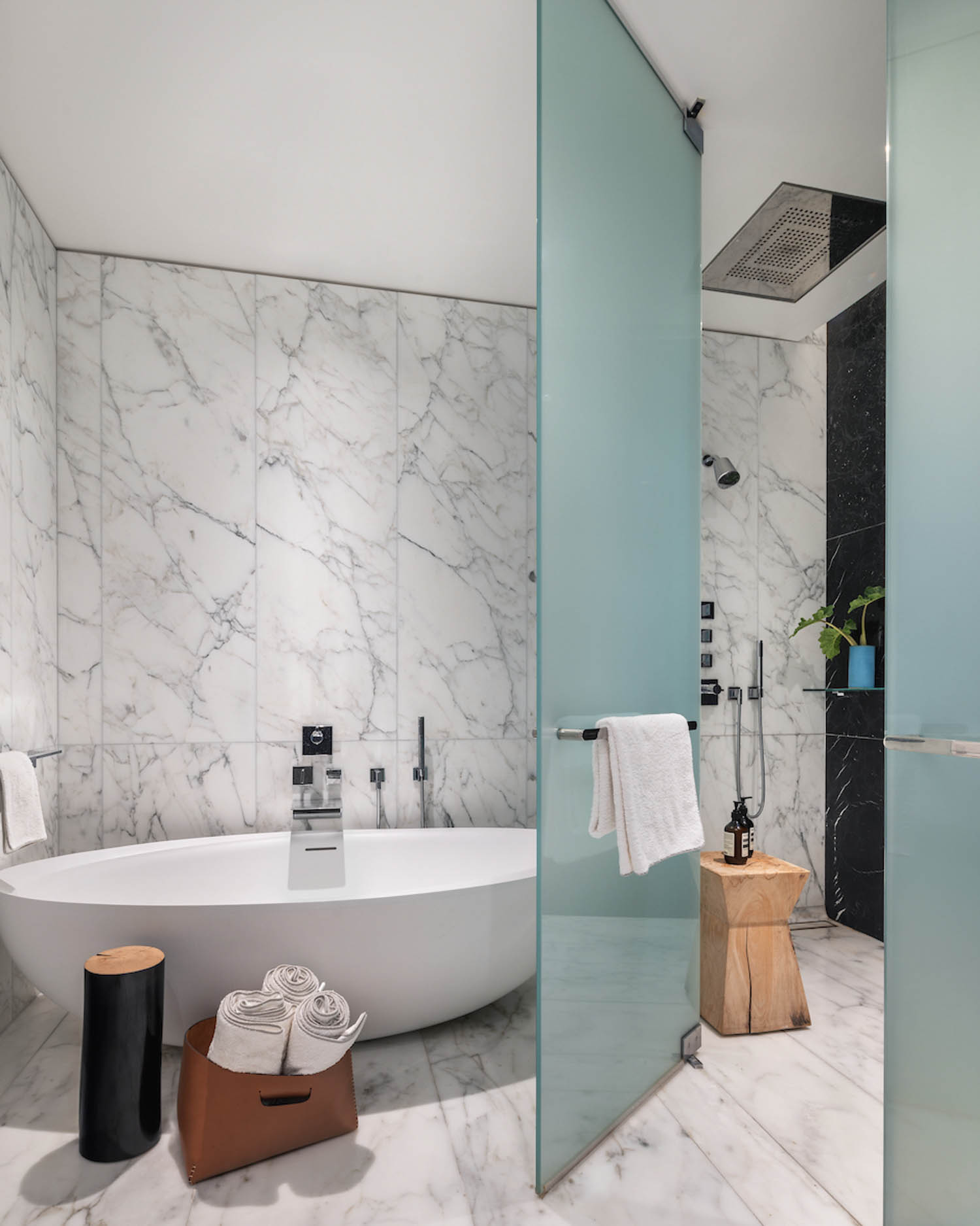 marble bathroom with white bathtub and frosted glass panels