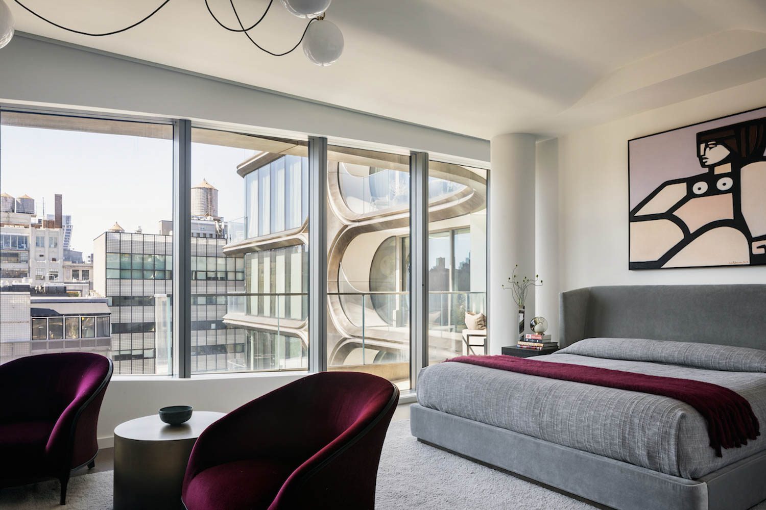 primary bedroom with view of the city, dark magenta velvet armchairs and artwork