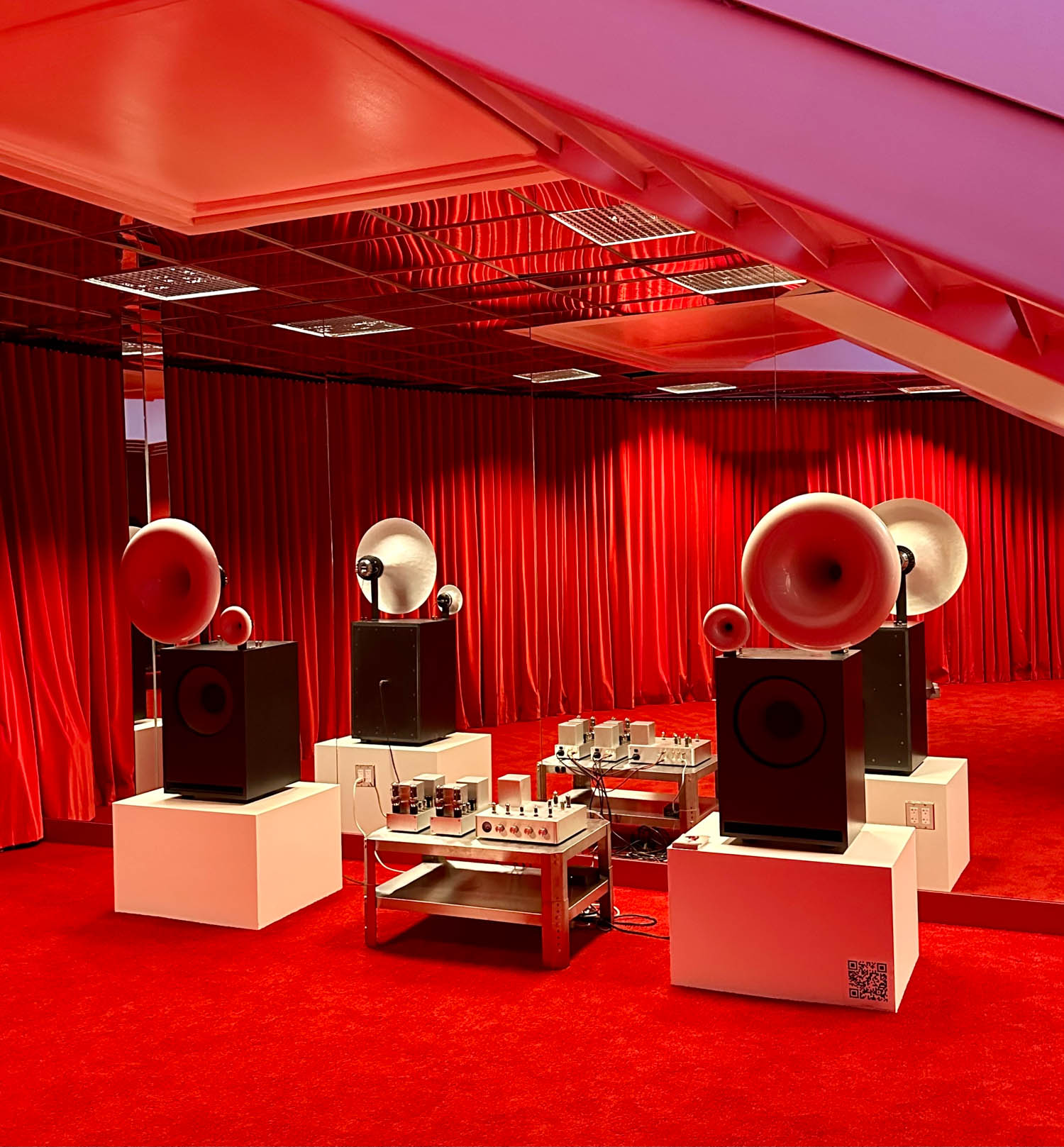 display showroom with dark speakers and all red drapes and carpet