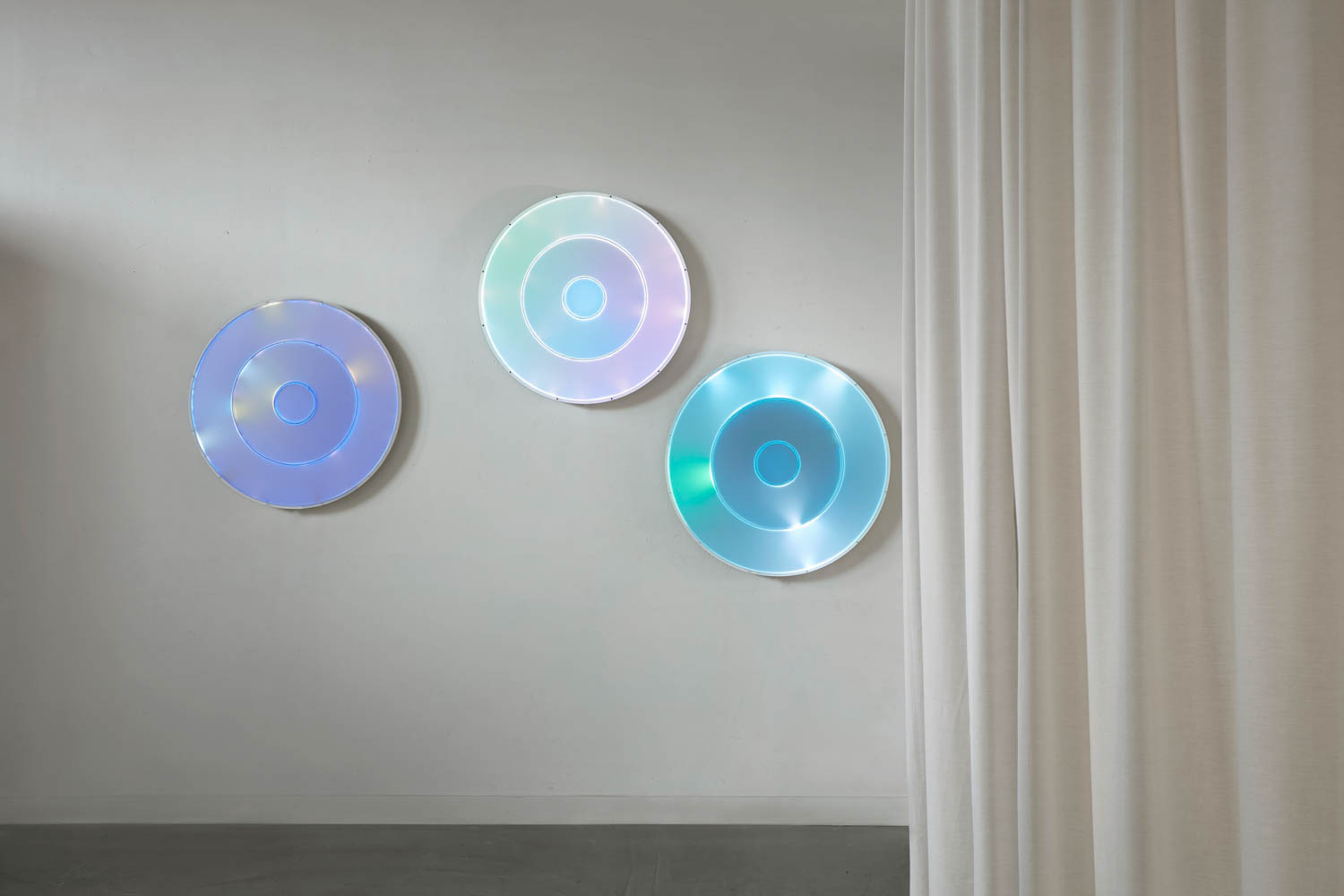 holographic circular disks on the wall next to a white drape