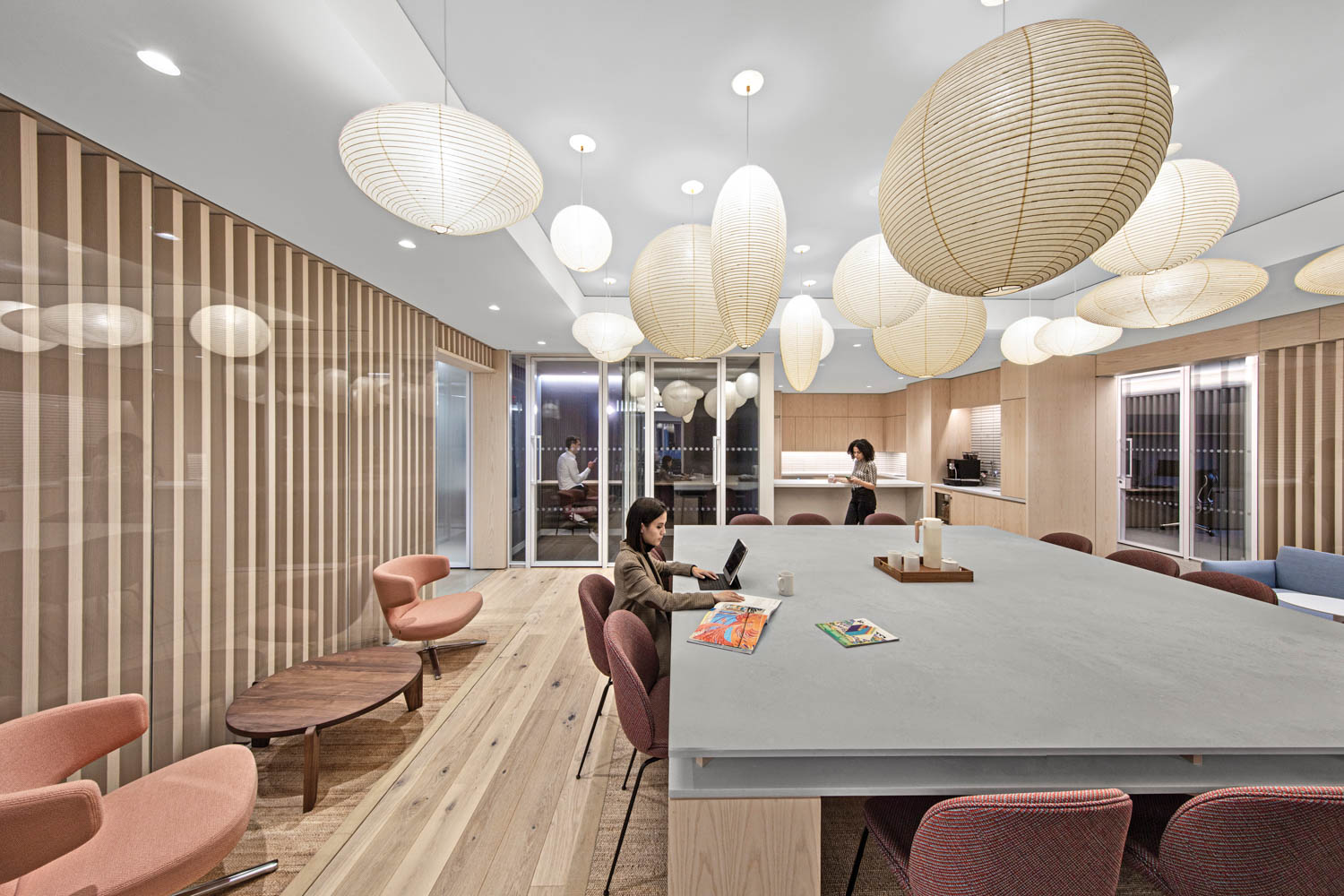 room with quartz-topped worktable, red chairs, white oak walls and pendant lights