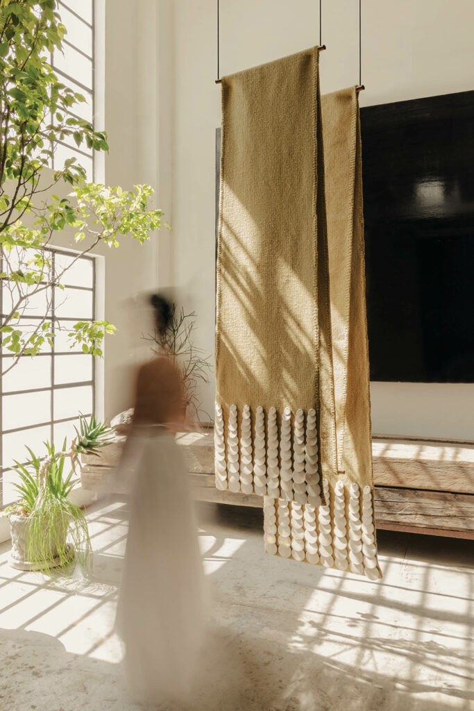 woman walking in front of a long scarf-like textile