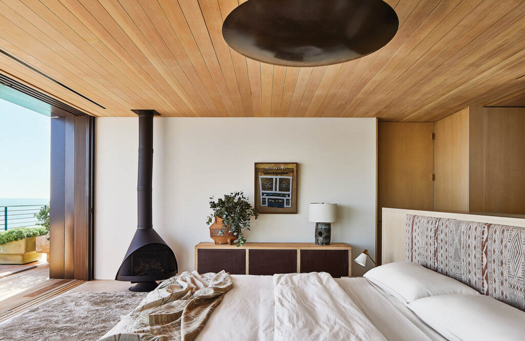 bedroom with black chimney, ceiling planks and white-oak bed