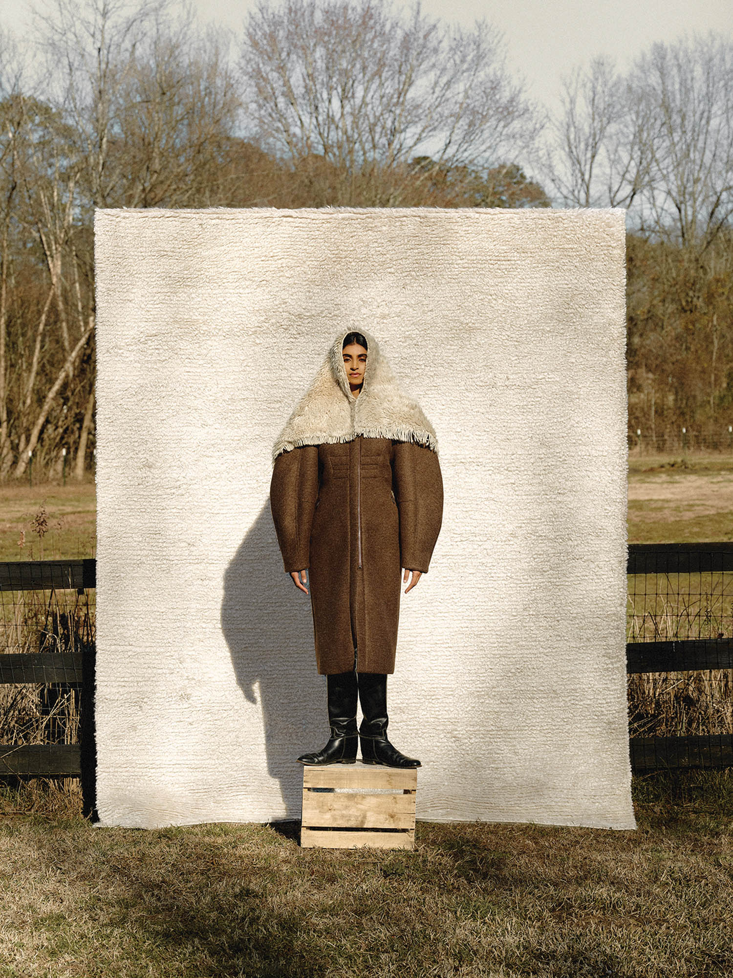 woman standing on a platform box with a wool capelet