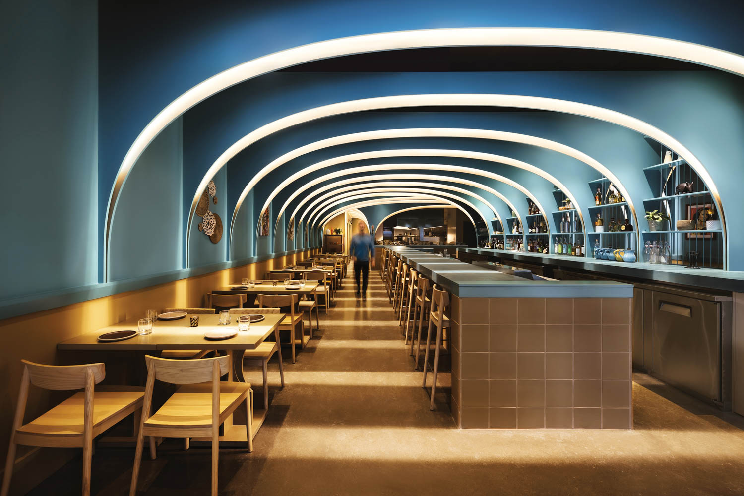 dining area with high blue arches and glass shelves