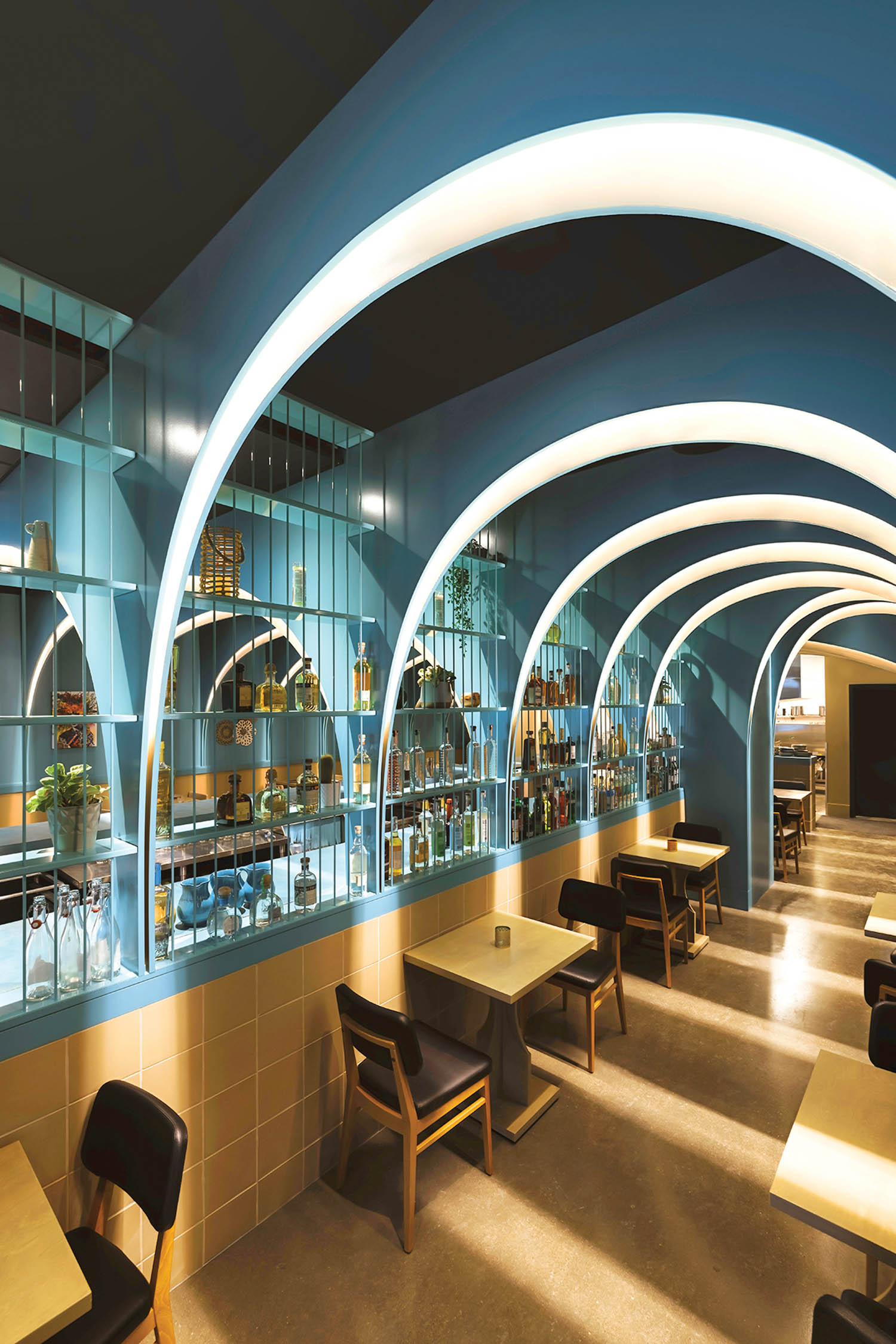 dining area with high blue ceilings and glass shelves with spirits