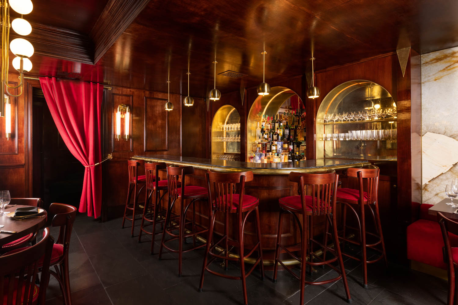 the bar area with mahogany red bar stools, gold countertop and lots of alcohol