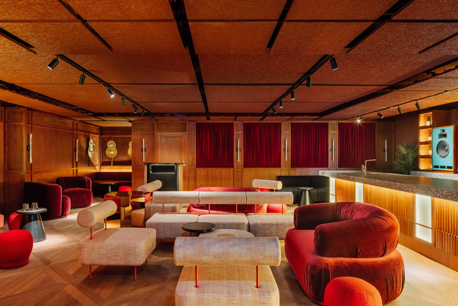 sitting area with dark red couches, white chairs and wooden ceiling