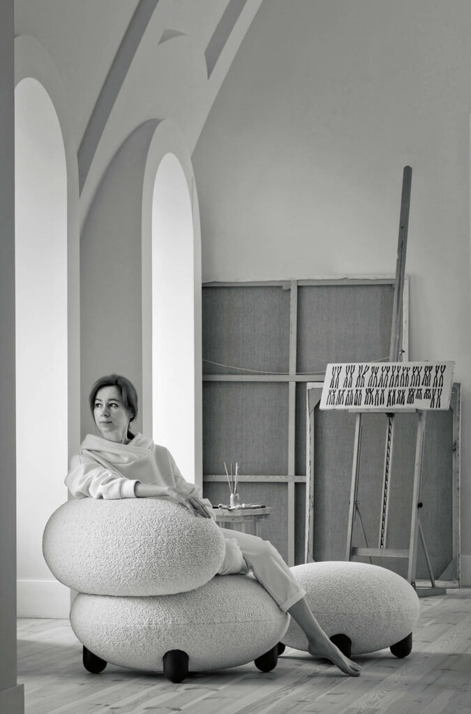 a designer sitting on a bulbous cream lounge