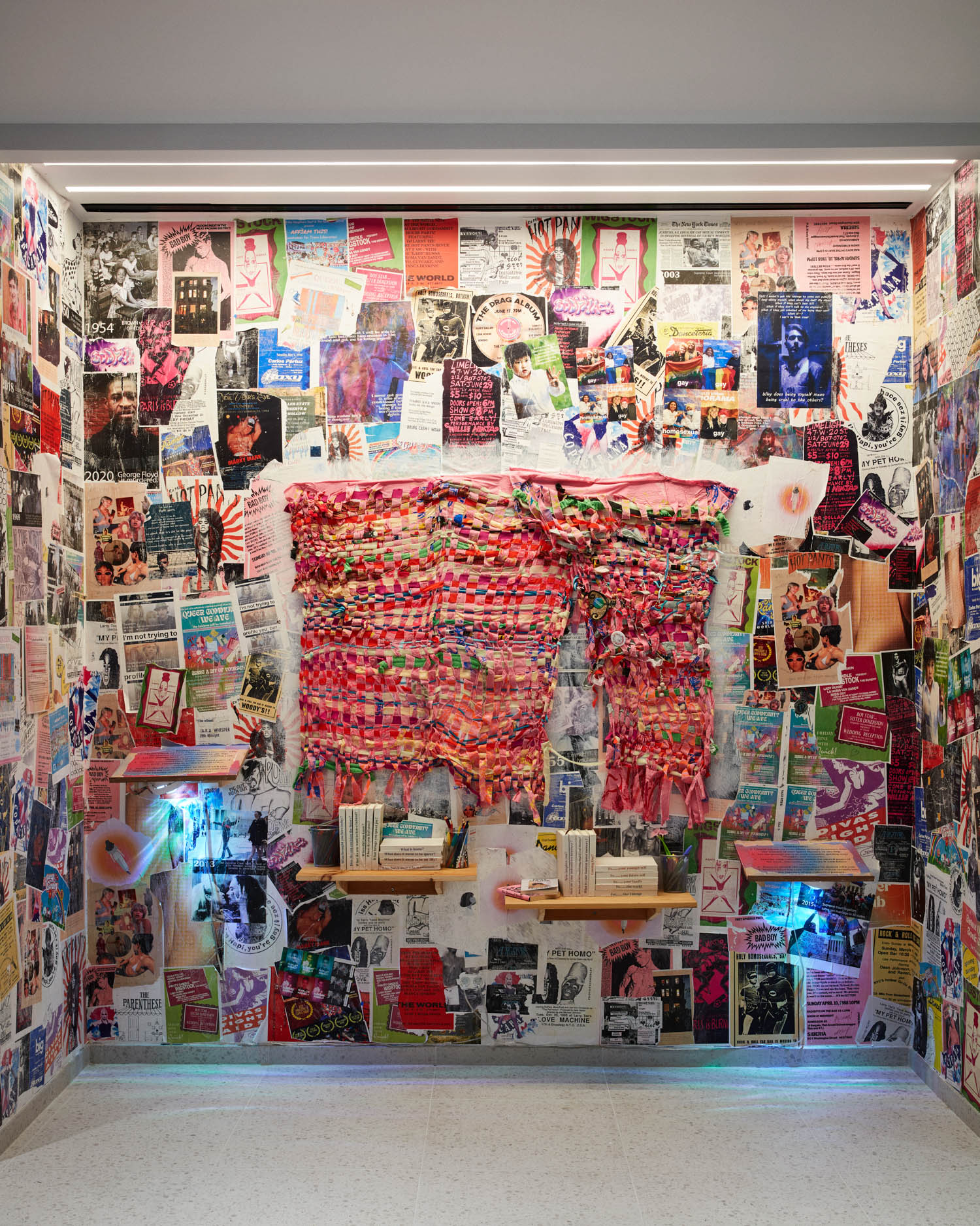 niche wall with collage of different pictures and posters and red scarf pinned in the middle