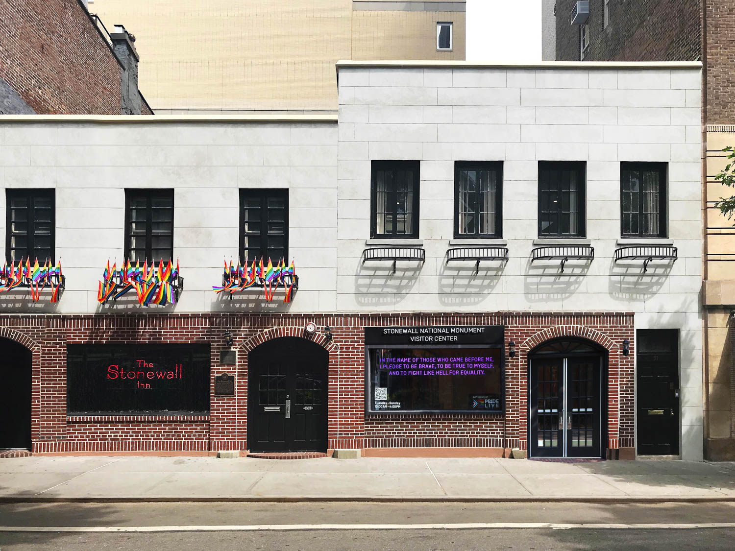 exterior of Stonewall National Monument Visitor Center with bright purple signage and lots of rainbow flags