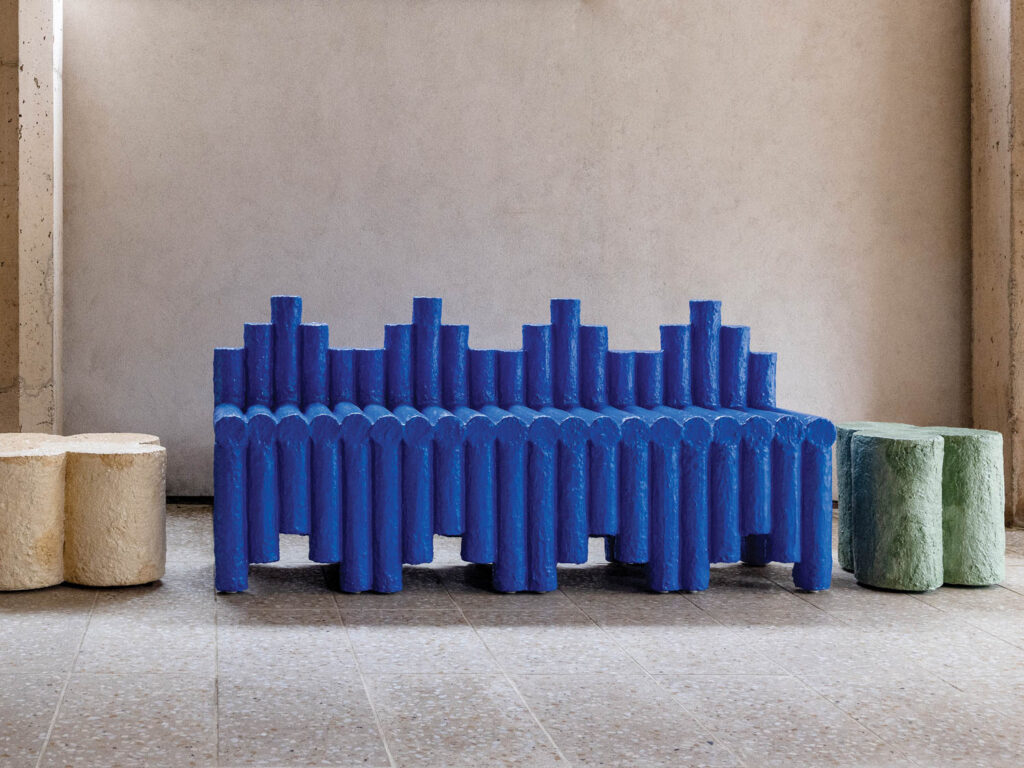 room with long blue bench made of circular blue poles and other tables nearby