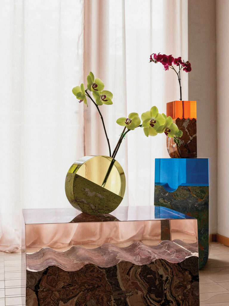 nook of living room with glass see through table, circular vase with orchids and other glass tables