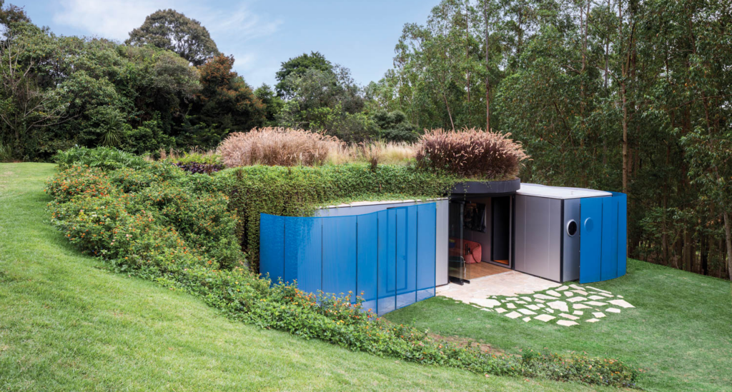 blue paneled building that is built into a grassy landscape